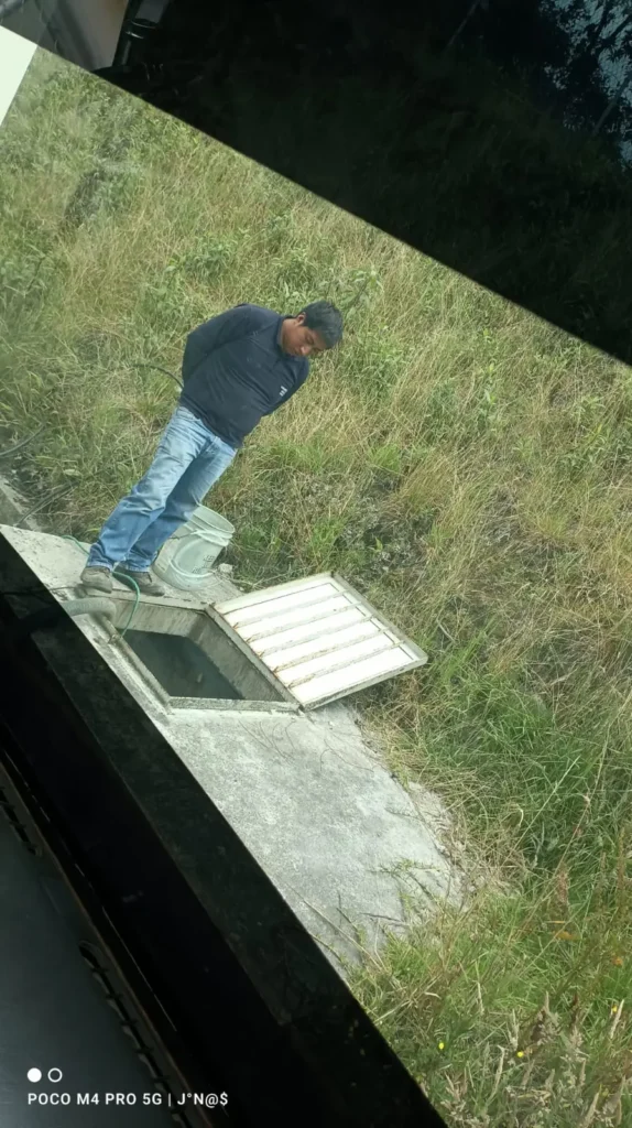 Operario inspección de limpieza de cisternas de agua subterránea abierta en una zona rural.